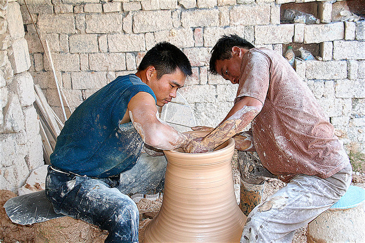 Zwei Dreher in Jingdezhen drehen die großen Ringe, aus denen später Monumentalvasen zusammengesetzt werden. Dieses Drehen in tandem erfordert perfekte Zusammenarbeit.
