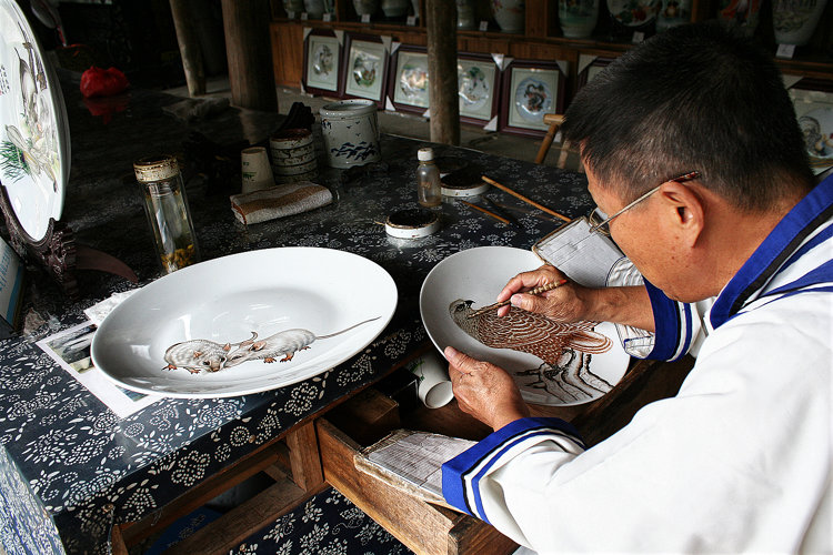 Dieser Porzellanmaler versieht Teller mit Tier–Sujets.
