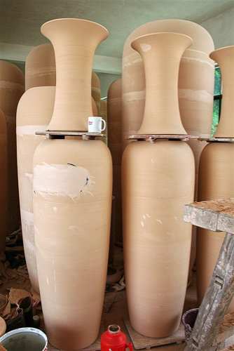 Unglasierte Monumentalvasen diverser Größen in verschiedenen Stadien ihrer Herstellung, teil bereits zusammengesetzt.